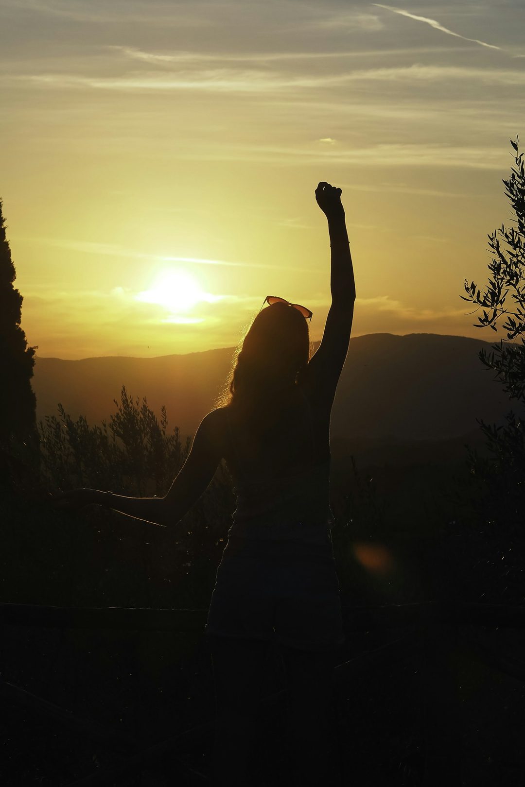 A woman raising her arms at sunrise — a symbol of hope and resilience